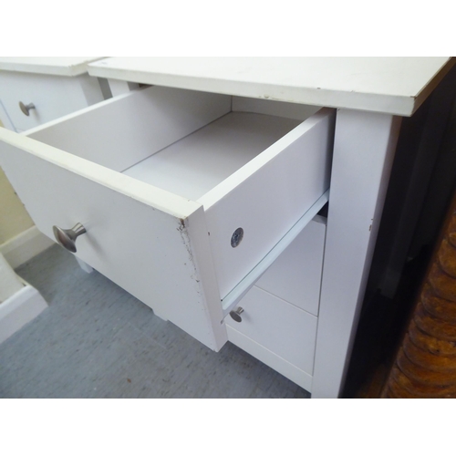 296 - A pair of modern white painted three drawer bedside chests, raised on square legs  24