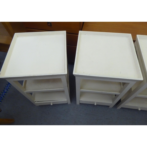 298 - A set of four modern cream painted, three tier occasional tables, raised on square legs  28