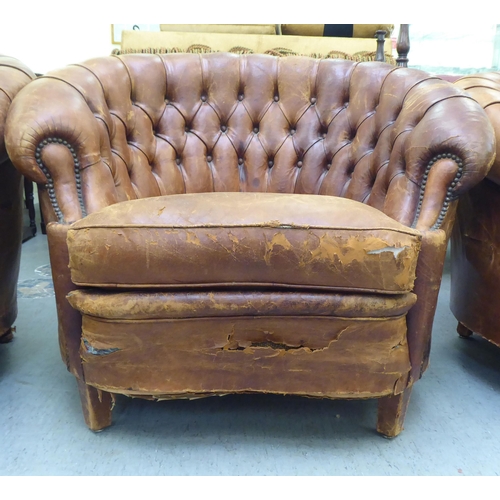 299 - A set of three early/mid 20thC stud and part button upholstered simulated brown hide armchairs, rais... 