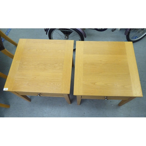 302 - A pair of modern light oak single drawer lamp tables, raised on square, tapered legs  20