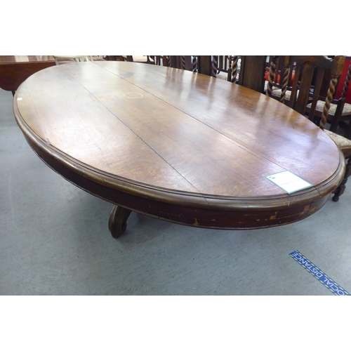 304 - An early 20thC oak pedestal table, the oval planked top raised on a carved C-scroll quadruped base&n... 