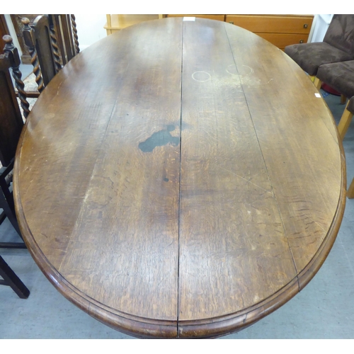 304 - An early 20thC oak pedestal table, the oval planked top raised on a carved C-scroll quadruped base&n... 