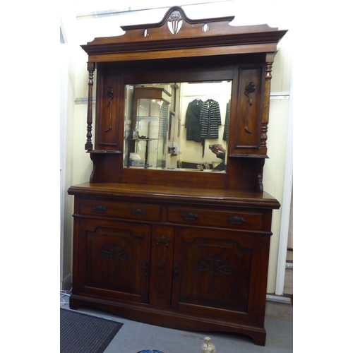311 - An Edwardian mahogany dresser, the superstructure with a mirrored panel, two open shelves, over two ... 
