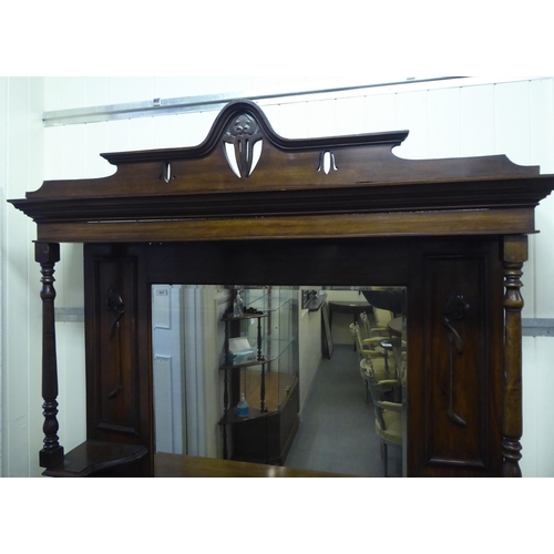 311 - An Edwardian mahogany dresser, the superstructure with a mirrored panel, two open shelves, over two ... 