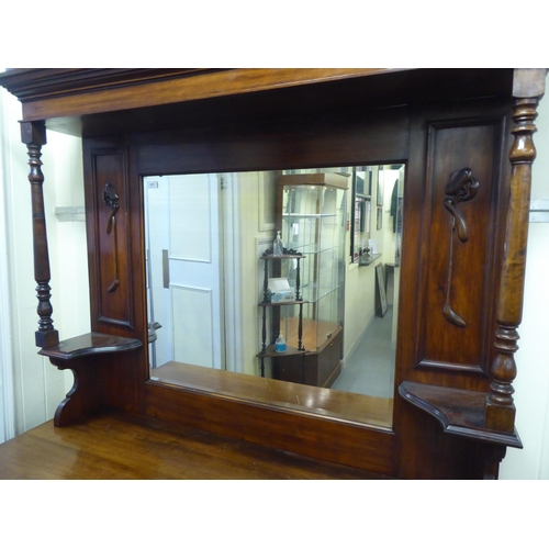 311 - An Edwardian mahogany dresser, the superstructure with a mirrored panel, two open shelves, over two ... 