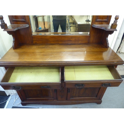 311 - An Edwardian mahogany dresser, the superstructure with a mirrored panel, two open shelves, over two ... 