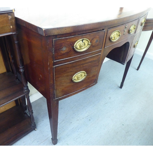 318 - A George III mahogany bow front sideboard with a central drawer, flanked by two cupboards, raised on... 