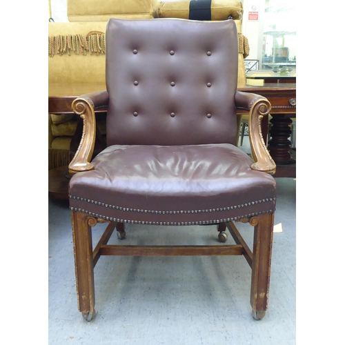 323 - A mid 20thC library style desk chair, part button upholstered in brown hide, raised on square forele... 