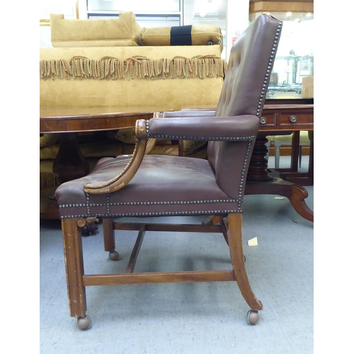 323 - A mid 20thC library style desk chair, part button upholstered in brown hide, raised on square forele... 