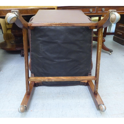 323 - A mid 20thC library style desk chair, part button upholstered in brown hide, raised on square forele... 