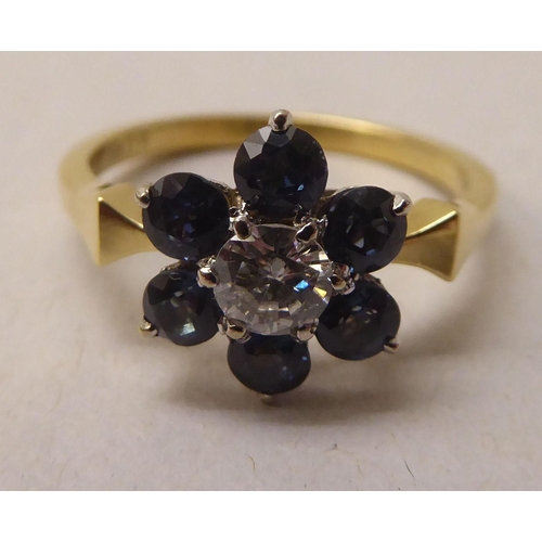 337 - A gold coloured metal ring, fashioned as a flower, claw set with a central diamond and blue stone pe... 
