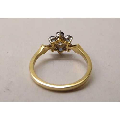 337 - A gold coloured metal ring, fashioned as a flower, claw set with a central diamond and blue stone pe... 