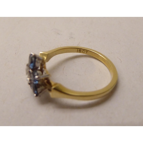 337 - A gold coloured metal ring, fashioned as a flower, claw set with a central diamond and blue stone pe... 