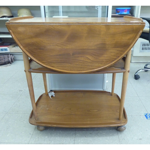 348 - An Ercol light elm, two tier tea trolley with fall flaps, raised on casters&nbsp; 30
