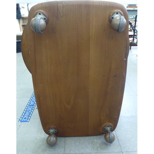 348 - An Ercol light elm, two tier tea trolley with fall flaps, raised on casters&nbsp; 30