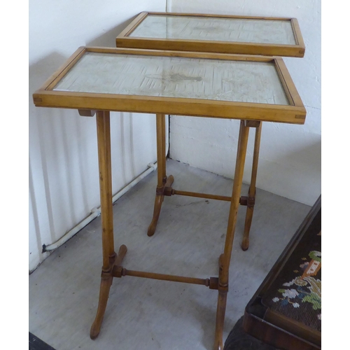 61 - A pair of early 20thC bleached mahogany framed occasional tables, the glazed floral fabric tops rais... 