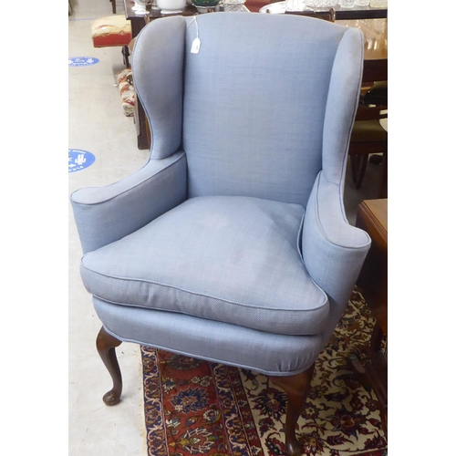 68 - An early 20thC Georgian style and later fabric upholstered, wingback enclosed armchair, raised on st... 