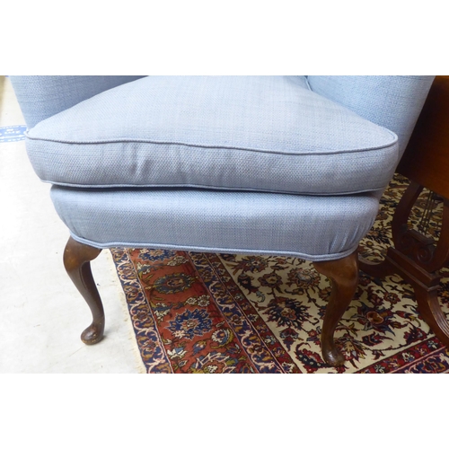 68 - An early 20thC Georgian style and later fabric upholstered, wingback enclosed armchair, raised on st... 