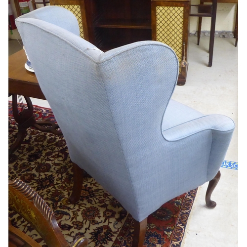 68 - An early 20thC Georgian style and later fabric upholstered, wingback enclosed armchair, raised on st... 