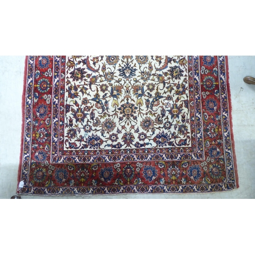 70 - A Persian rug, decorated with flora and foliate designs, on a multi-coloured ground  58