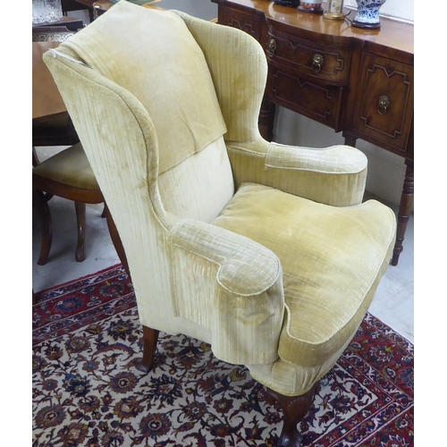 71 - An early 20thC Georgian style and later fabric upholstered, wingback, enclosed armchair, raised on C... 