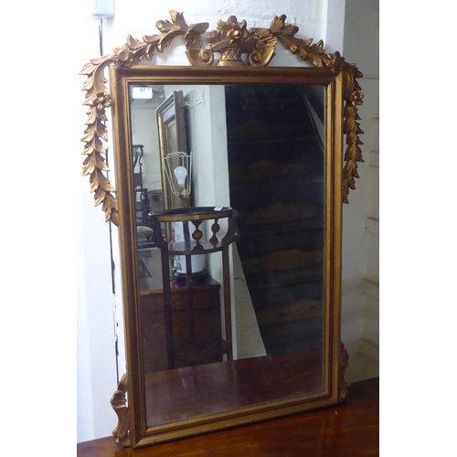 87 - A 20thC mirror, the plate set in a vase and foliate moulded gilt frame  35