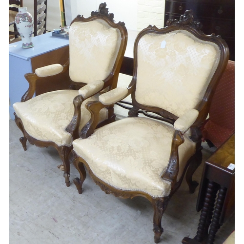 93 - A pair of late Victorian style walnut showwood framed open arm salon chairs, upholstered in two tone... 