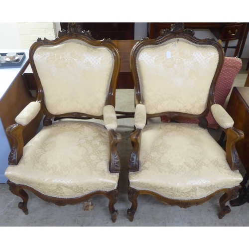 93 - A pair of late Victorian style walnut showwood framed open arm salon chairs, upholstered in two tone... 