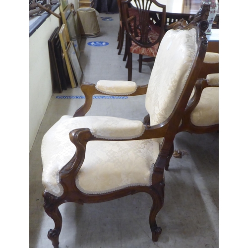 93 - A pair of late Victorian style walnut showwood framed open arm salon chairs, upholstered in two tone... 