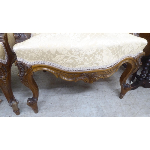 93 - A pair of late Victorian style walnut showwood framed open arm salon chairs, upholstered in two tone... 