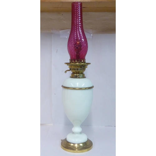 149 - An early 20thC pale green china and brass mounted table pedestal lamp with a cranberry coloured glas... 