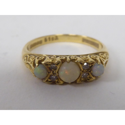 165 - An 18ct gold ring, set with three cabochon opals, interspersed with diamonds&nbsp;