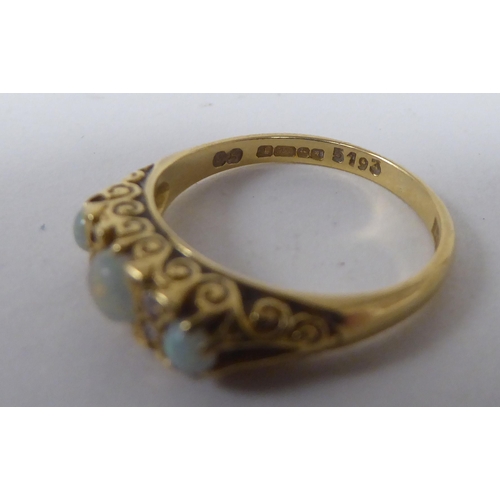 165 - An 18ct gold ring, set with three cabochon opals, interspersed with diamonds&nbsp;