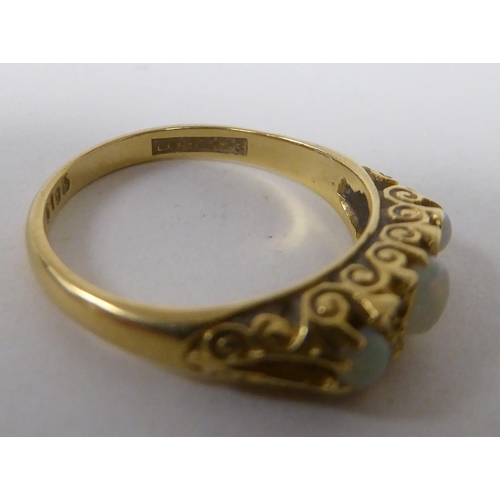 165 - An 18ct gold ring, set with three cabochon opals, interspersed with diamonds&nbsp;