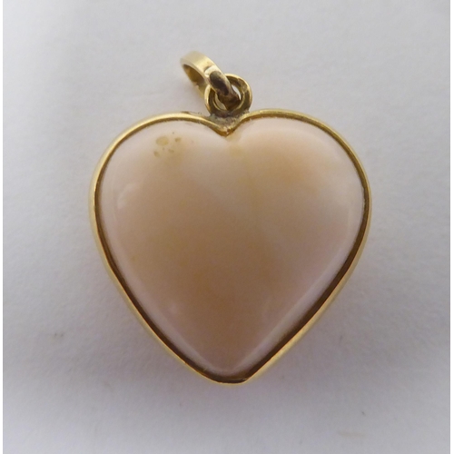 169 - A coral pendant, fashioned as a love heart, set in a yellow metal mount&nbsp; stamped K18