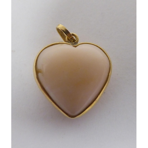 169 - A coral pendant, fashioned as a love heart, set in a yellow metal mount&nbsp; stamped K18