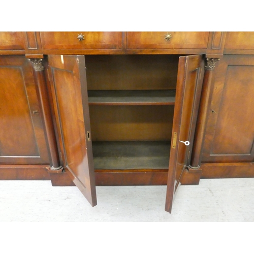 173 - A Regency style mahogany breakfront sideboard with applied pilasters and a mottled grey/white marble... 
