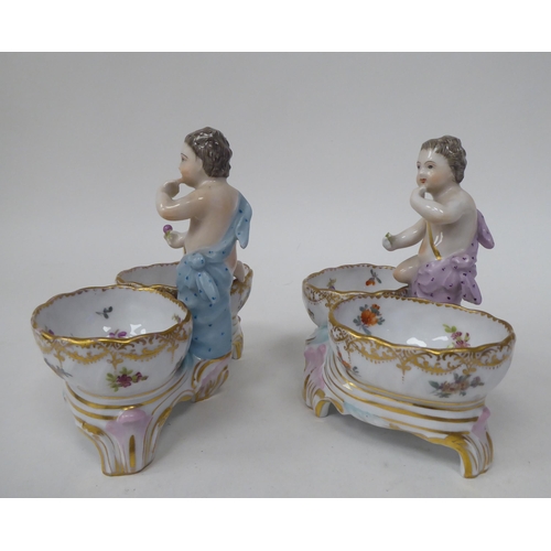 92 - A pair of 20thC Dresden porcelain double salt cellars, featuring a cherubic figure with floral decor... 