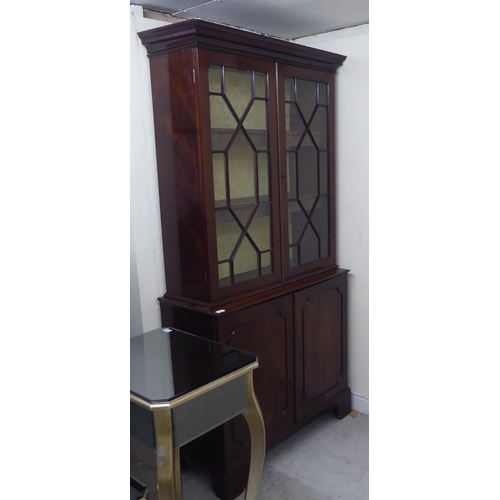 176 - A Regency style two part mahogany cabinet bookcase with a straight cornice, over a pair of astragal ... 