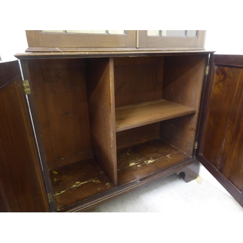 176 - A Regency style two part mahogany cabinet bookcase with a straight cornice, over a pair of astragal ... 