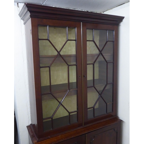 176 - A Regency style two part mahogany cabinet bookcase with a straight cornice, over a pair of astragal ... 