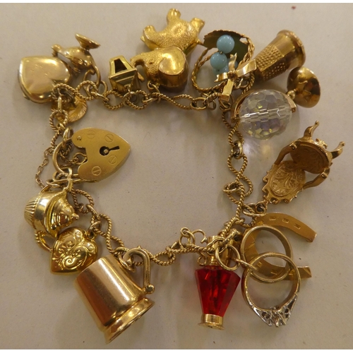 135 - A 9ct and gold coloured metal charm bracelet, on a padlock clasp