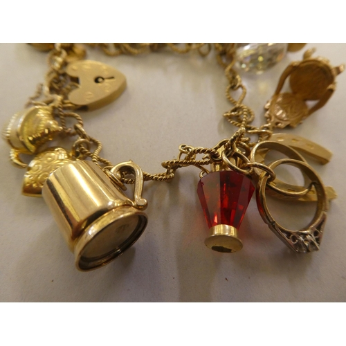 135 - A 9ct and gold coloured metal charm bracelet, on a padlock clasp