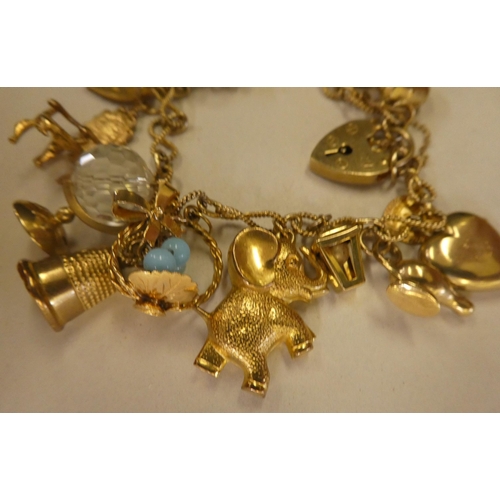 135 - A 9ct and gold coloured metal charm bracelet, on a padlock clasp