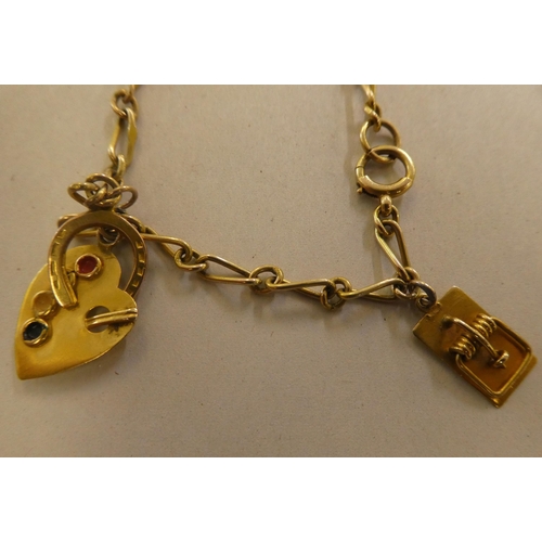 146 - Two 9ct gold, gold coloured and other metal charms, on bracelets, one with a padlock clasp