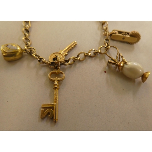 146 - Two 9ct gold, gold coloured and other metal charms, on bracelets, one with a padlock clasp