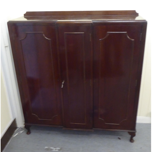 179 - A mid 20thC mahogany breakfront cabinet with three panelled doors, raised on cabriole legs  52