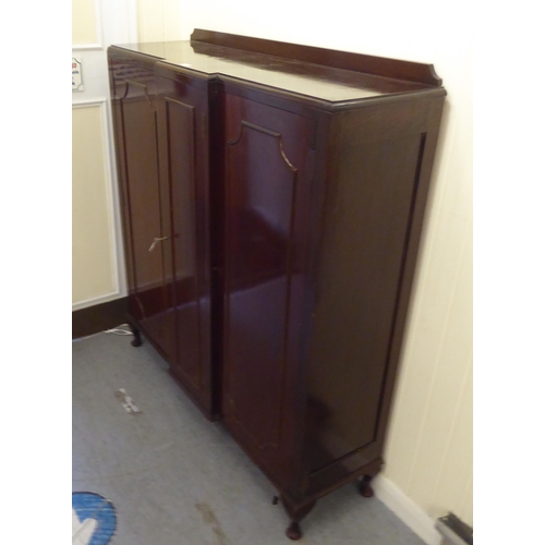 179 - A mid 20thC mahogany breakfront cabinet with three panelled doors, raised on cabriole legs  52