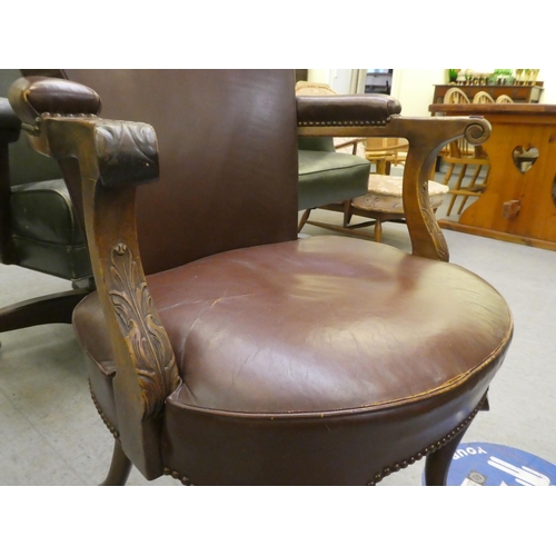 185 - An early 20thC mahogany framed desk chair with a brown hide upholstered back and seat, raised on cab... 