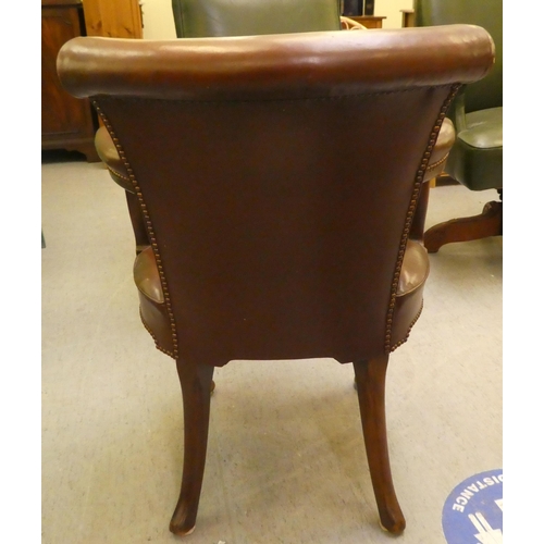 185 - An early 20thC mahogany framed desk chair with a brown hide upholstered back and seat, raised on cab... 